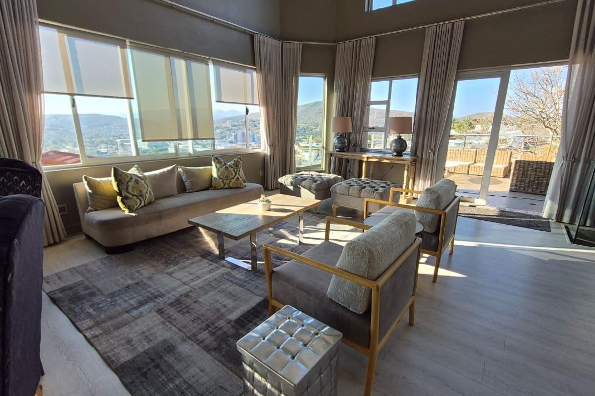 Spacious living room featuring high ceilings, large windows with panoramic views, and direct access to an outdoor patio area.