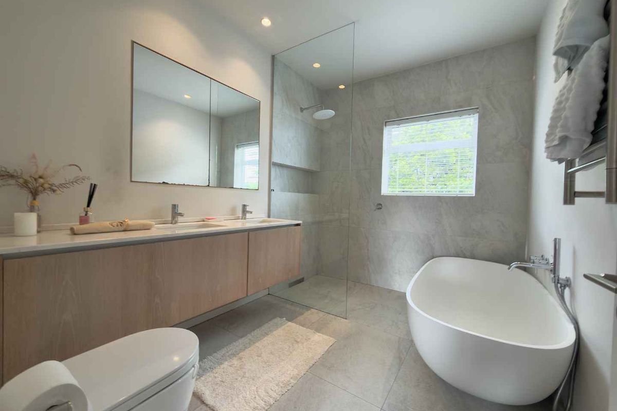 Modern bathroom featuring a double vanity, freestanding bathtub, walk-in shower with glass screen, and high-quality stone-look tiling throughout.