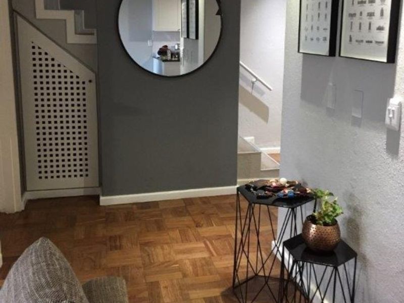 A well-maintained hallway featuring classic parquet flooring and a convenient under-stair storage cupboard, providing a functional and welcoming entrance area.