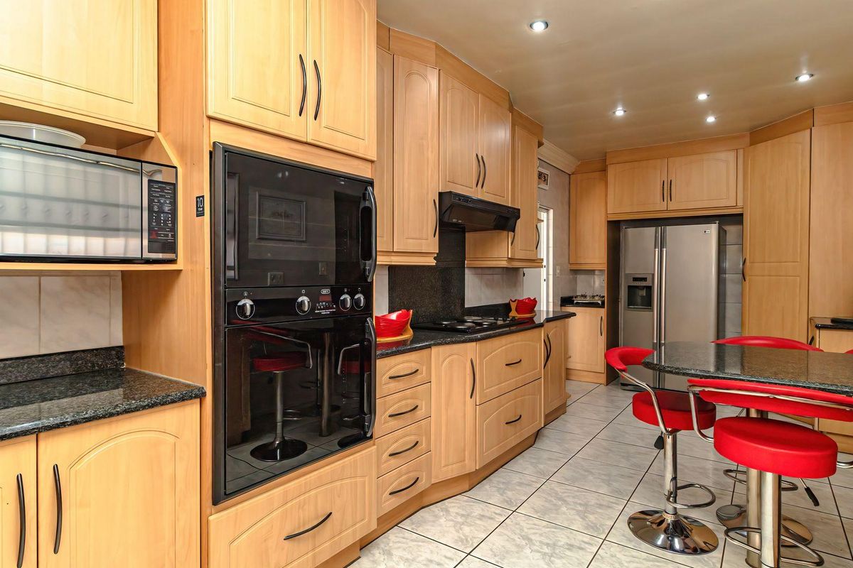 A well-appointed kitchen featuring light wood cabinetry, granite countertops, integrated appliances including an oven and microwave, and tiled flooring.