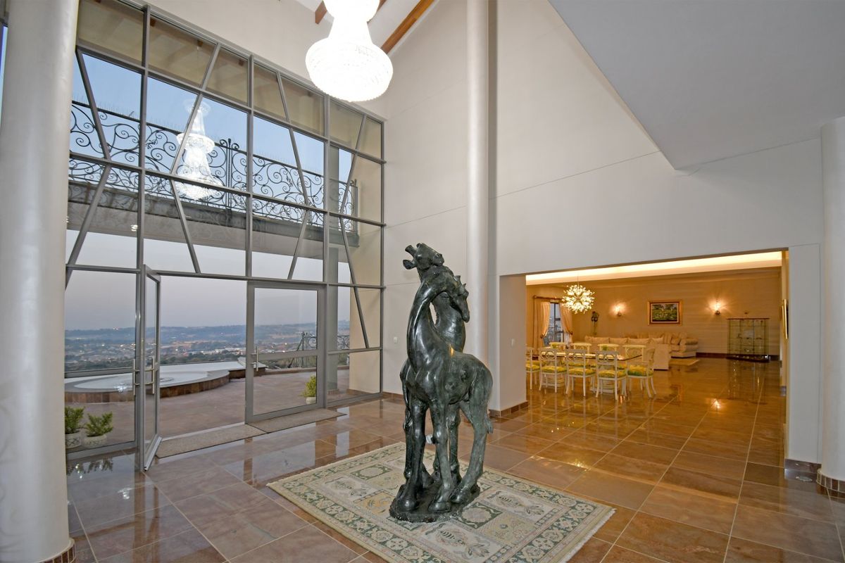 Spacious double-volume living area featuring expansive floor-to-ceiling glass windows, polished tile flooring, and seamless flow to the adjacent dining space and outdoor balcony.