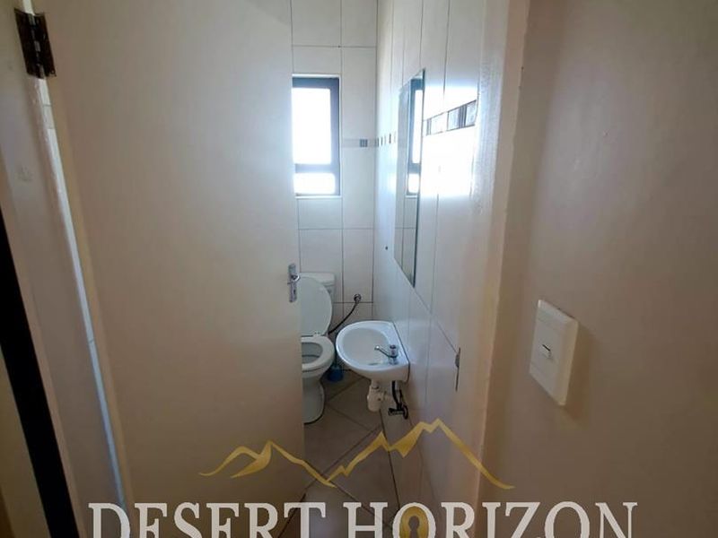 A compact, functional bathroom featuring tiled walls and flooring, a wall-mounted basin, and a standard toilet.
