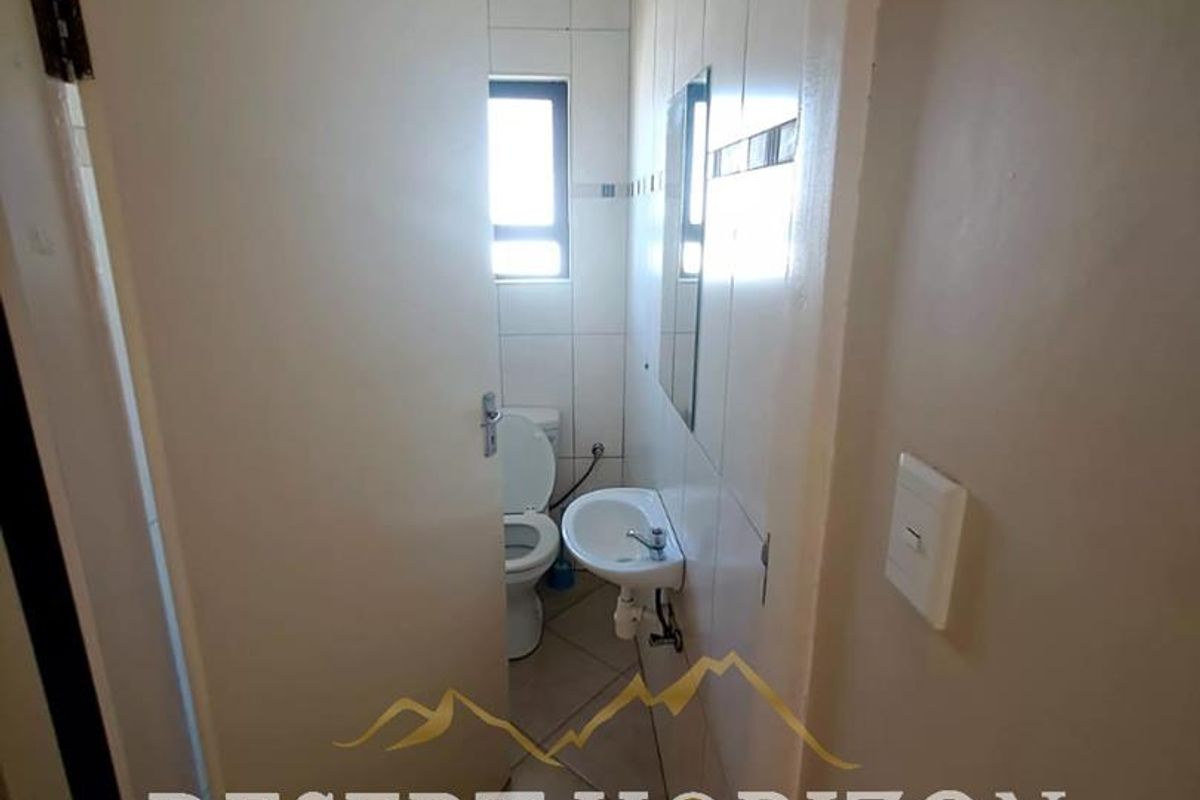 A compact, functional bathroom featuring tiled walls and flooring, a wall-mounted basin, and a standard toilet.