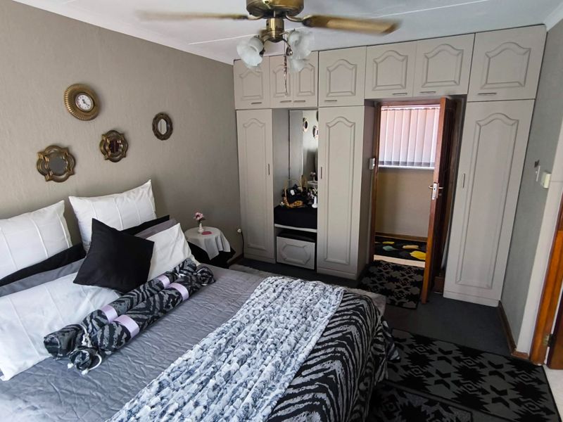 A bedroom featuring built-in cupboards with a central mirrored vanity and a ceiling fan.