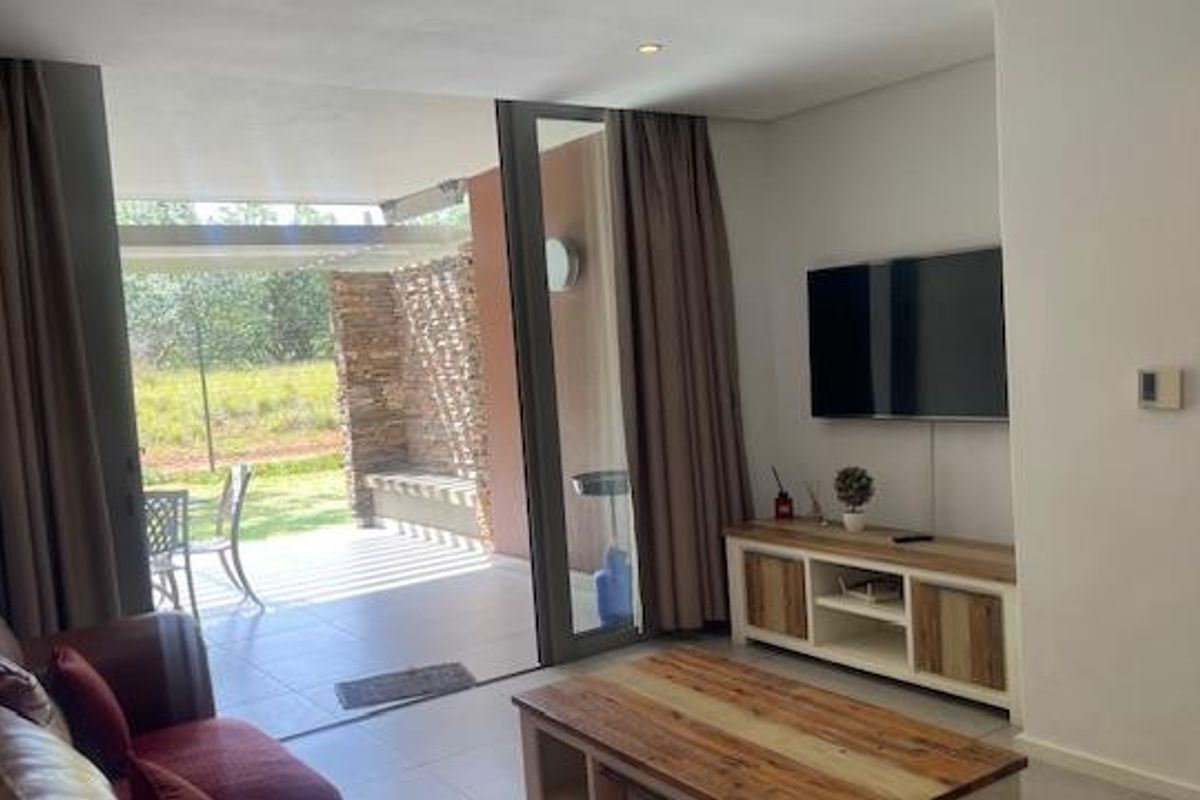 A bright living room featuring large sliding glass doors that open onto a covered patio, creating a seamless indoor-outdoor flow.