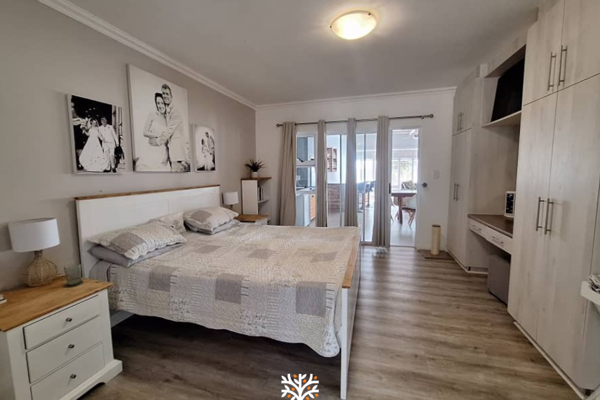 Spacious bedroom featuring light wood-look flooring, built-in cabinetry with integrated desk space, and sliding glass doors providing access to an outdoor patio area.