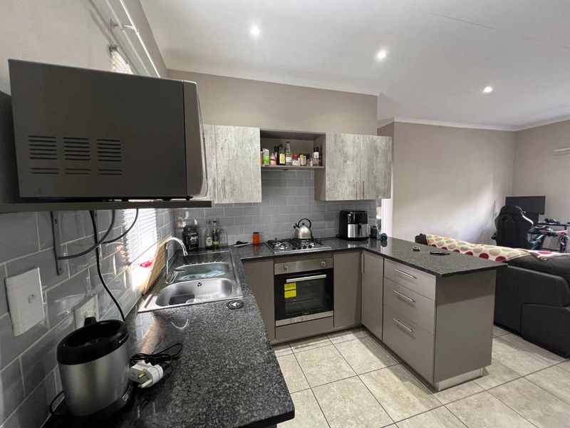Open-plan kitchen featuring granite countertops, subway tile backsplash, built-in oven, gas hob, and modern cabinetry, seamlessly flowing into the adjacent living area.