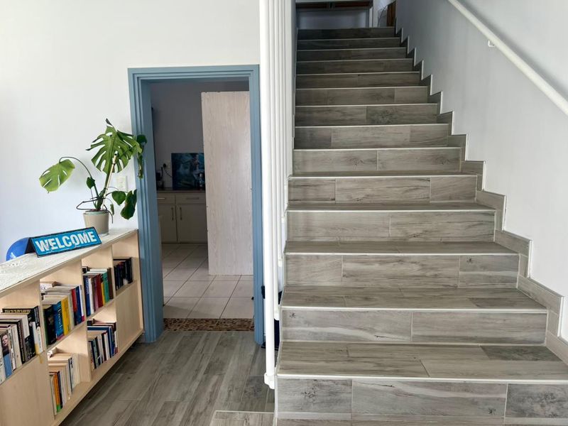Interior view featuring a staircase with wood-look tile treads and a doorway leading to an adjacent room with tiled flooring.