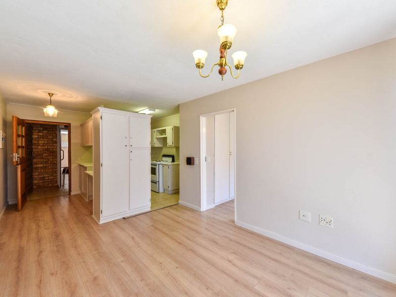 An open-plan living and kitchen area featuring light laminate flooring, neutral walls, and built-in cabinetry, offering a clean and functional space.