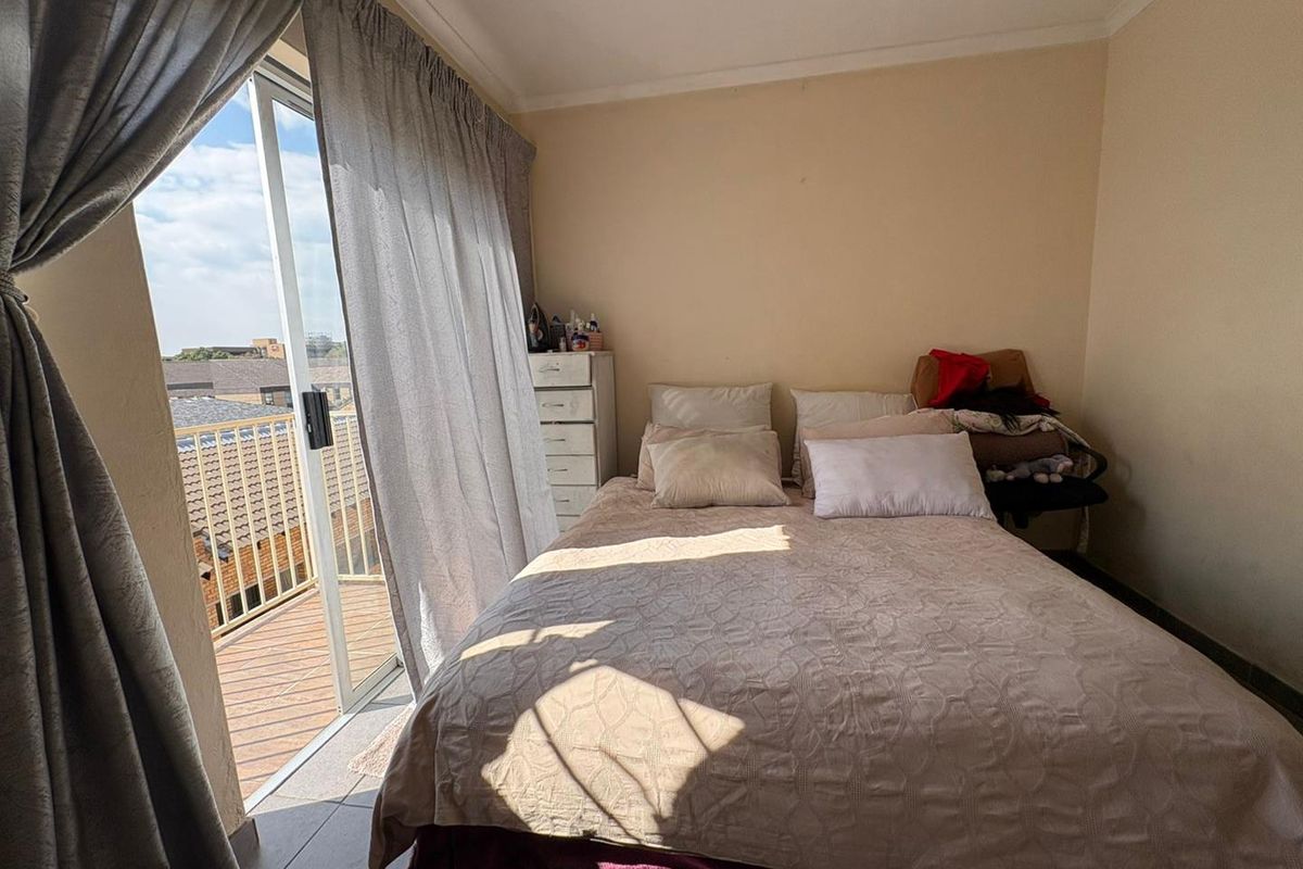 A bedroom featuring tiled flooring and a sliding glass door that opens onto a private balcony with outdoor views.