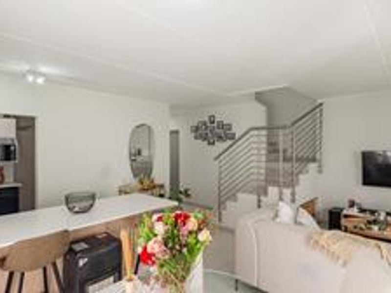 Open-plan living area featuring a modern kitchen with a central island, built-in appliances, and a staircase with a contemporary metal balustrade.