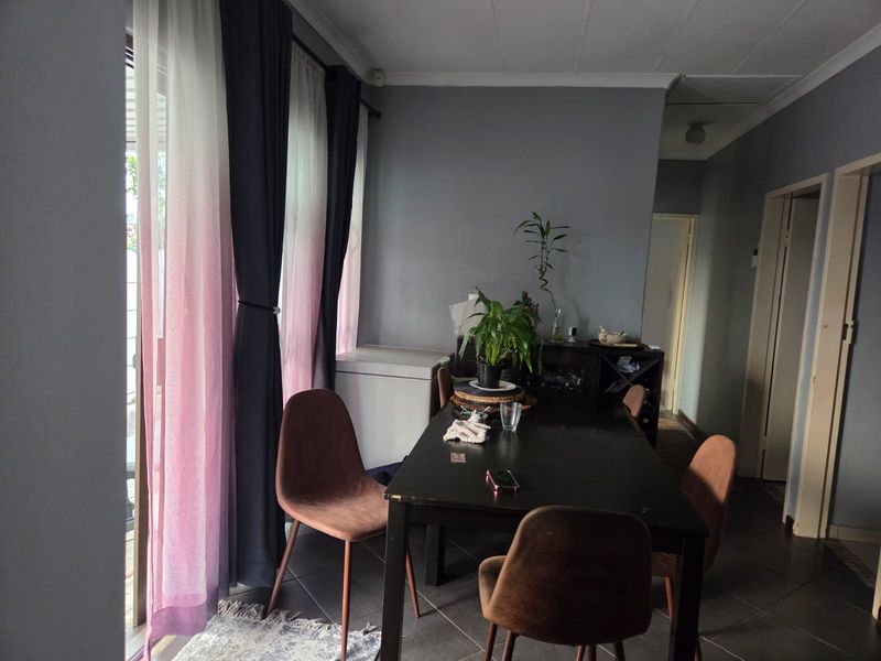 A dining area featuring tiled flooring and a sliding glass door providing natural light.
