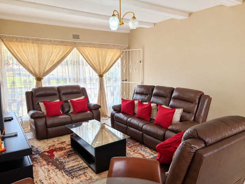 A comfortable living room featuring exposed ceiling beams, a security gate, and large sliding doors that provide natural light.