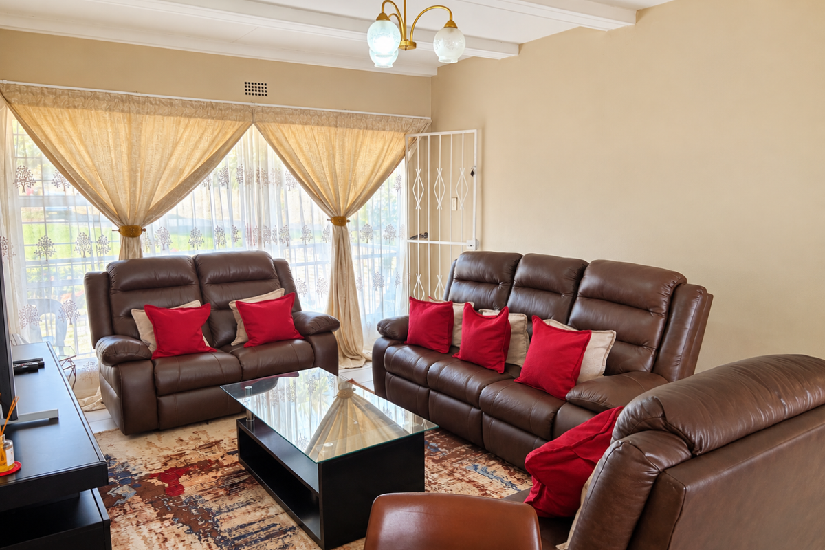A comfortable living room featuring exposed ceiling beams, a security gate, and large sliding doors that provide natural light.