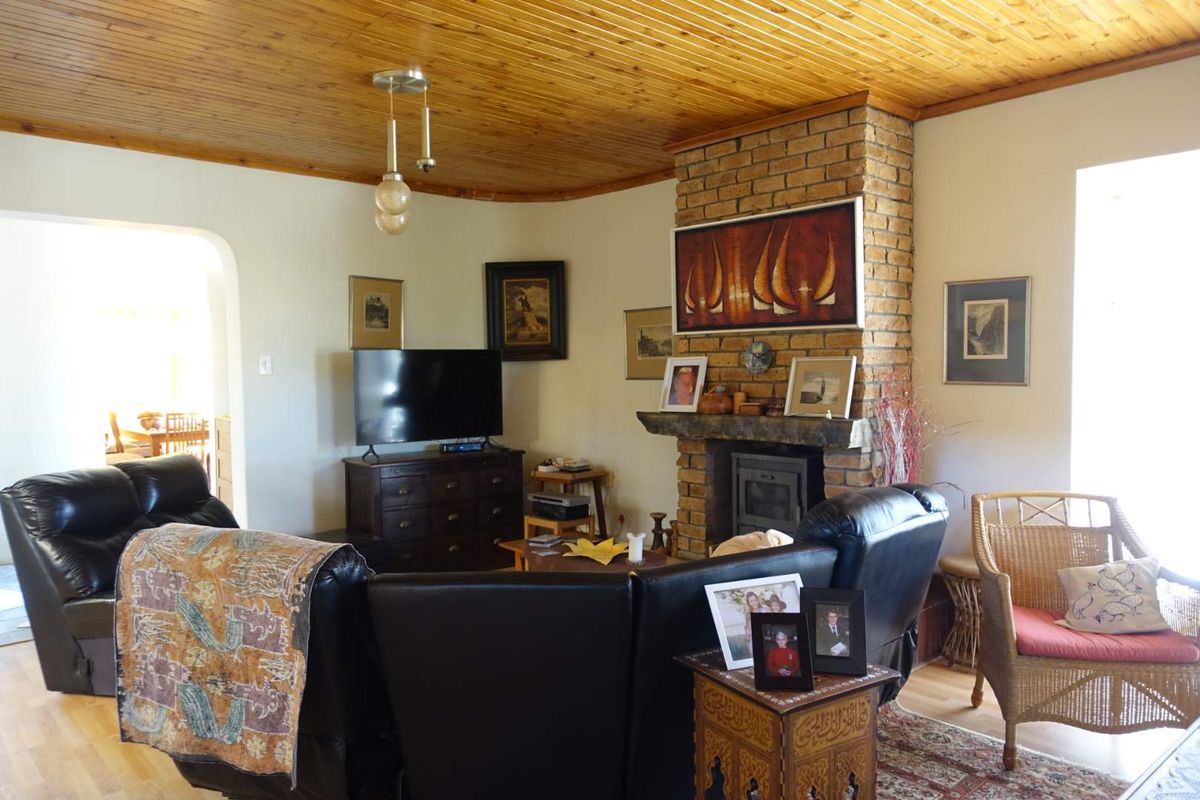 A cozy living room featuring a prominent face-brick fireplace with a built-in wood-burning stove and a warm timber-clad ceiling.