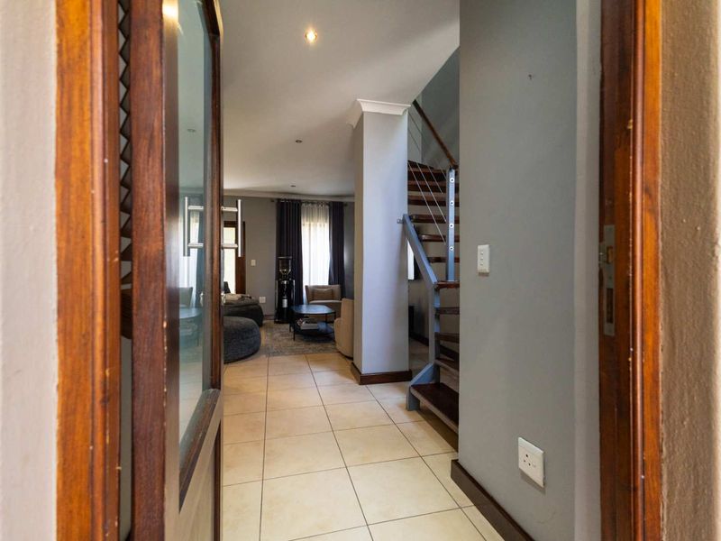 Welcoming entrance hall featuring tiled flooring and a modern staircase with metal balustrades, leading into the open-plan living area.