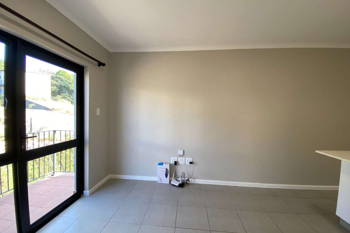 An empty living area featuring neutral tiled flooring, a sliding glass door leading to a balcony, and integrated electrical and data connectivity points.