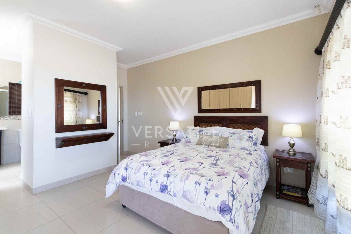 A well-maintained bedroom featuring neutral wall tones, tiled flooring, and an en-suite bathroom access.