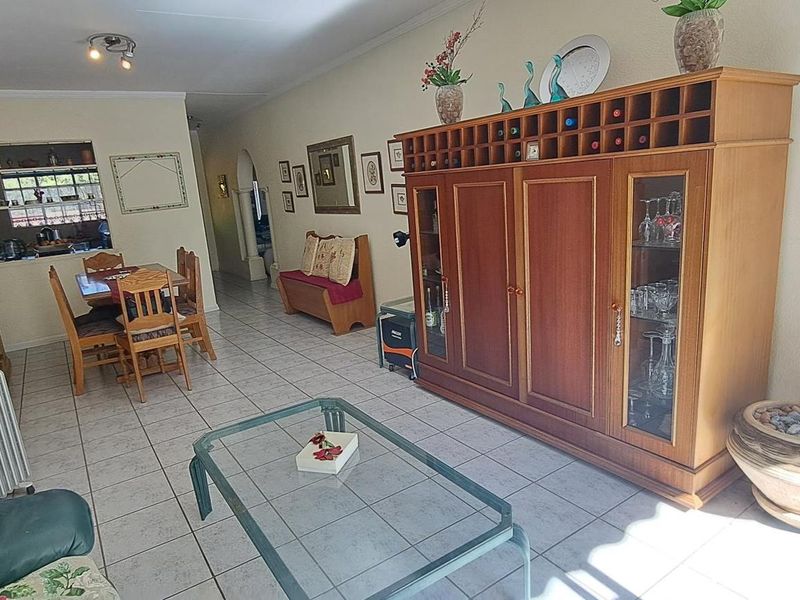 Open plan living and dining area featuring ceramic floor tiles, an interior archway, and a convenient pass-through window connecting to the kitchen.