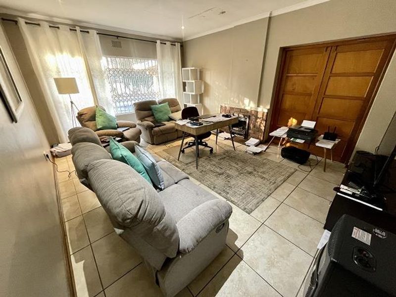 A living room featuring tiled flooring, a brick fireplace, and sliding wooden doors, with visible ceiling staining requiring attention.