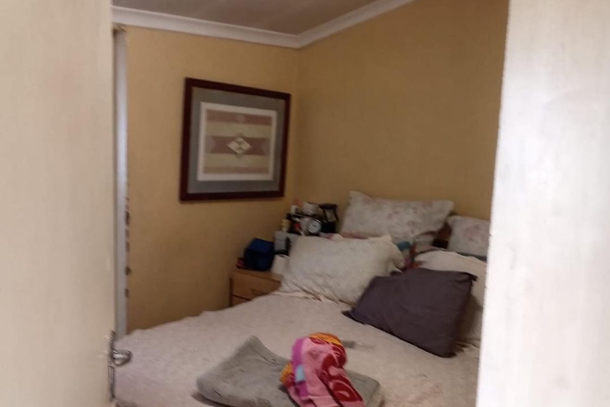 A compact bedroom featuring neutral wall tones and standard ceiling coving, viewed through a doorway.