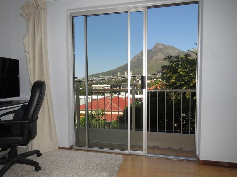 Bedroom featuring a sliding glass door that opens onto a balcony with scenic mountain and urban views.