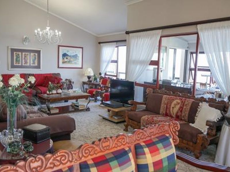 Spacious living room featuring a vaulted ceiling, elegant chandelier, and large sliding glass doors that provide natural light and access to the outdoor area.