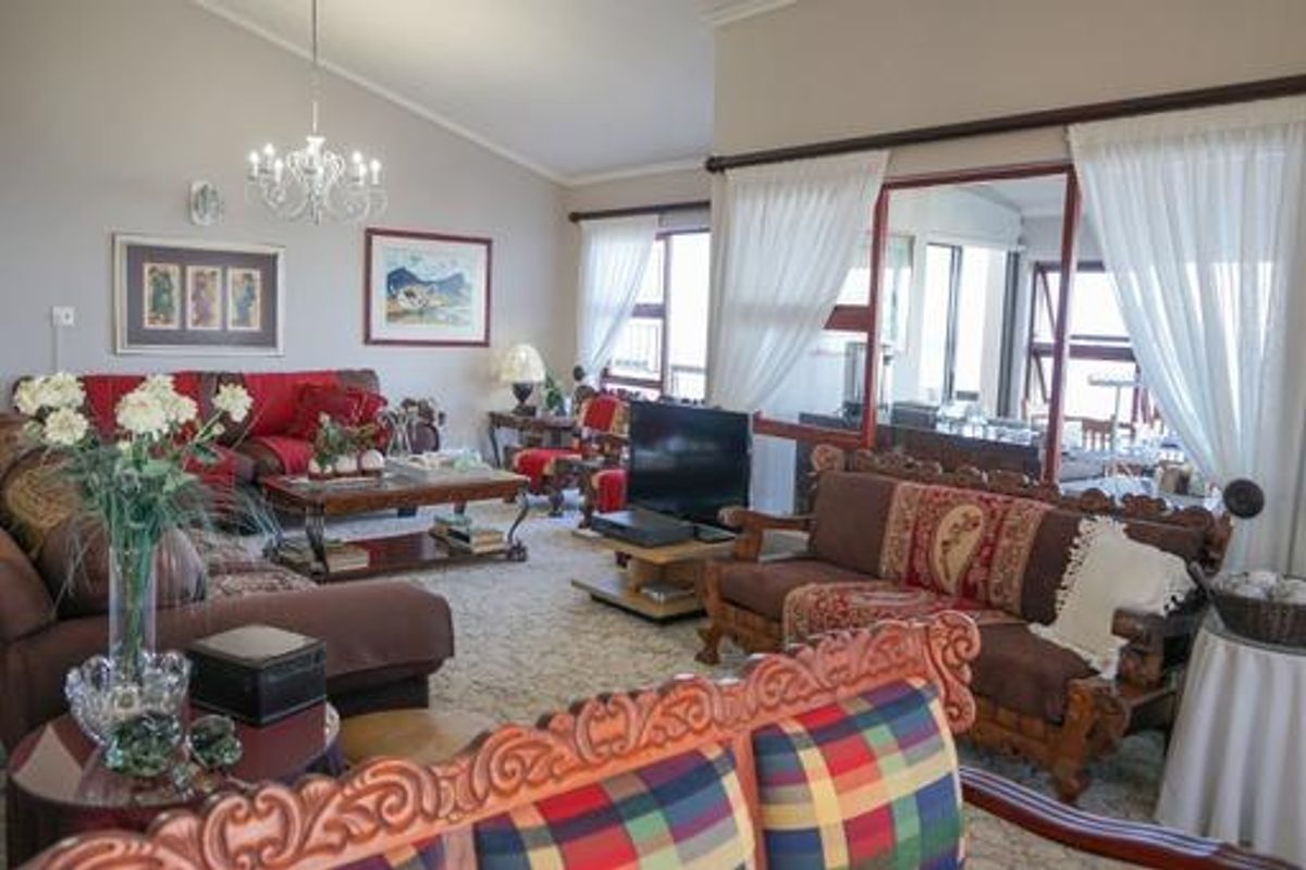 Spacious living room featuring a vaulted ceiling, elegant chandelier, and large sliding glass doors that provide natural light and access to the outdoor area.