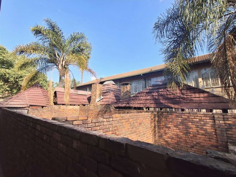 Rear exterior view of the townhouse complex featuring brick boundary walls and traditional tiled roofing with chimney stacks.