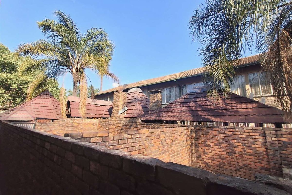 Rear exterior view of the townhouse complex featuring brick boundary walls and traditional tiled roofing with chimney stacks.
