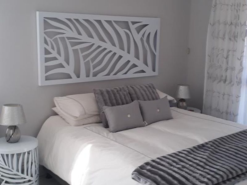 A well-maintained bedroom featuring neutral wall tones and clean tiled flooring, offering a bright and comfortable living space.