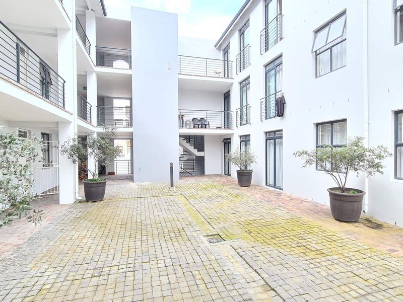 A view of the apartment complex courtyard featuring paved ground surfaces and multi-level balconies with metal railings.