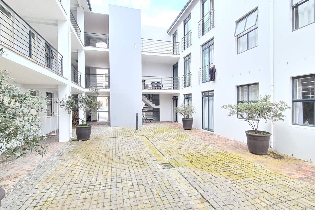 A view of the apartment complex courtyard featuring paved ground surfaces and multi-level balconies with metal railings.