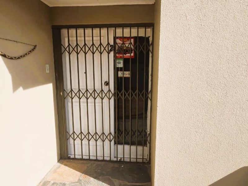 Entrance area featuring a metal security gate and a solid door with stone paved flooring.