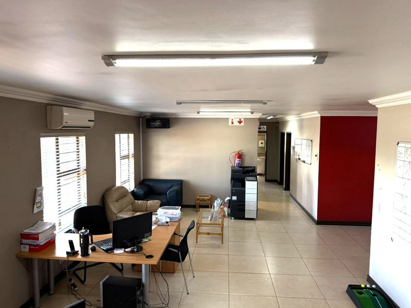 A functional office space featuring tiled flooring, split-system air conditioning, and overhead fluorescent lighting, providing a practical layout for professional use.
