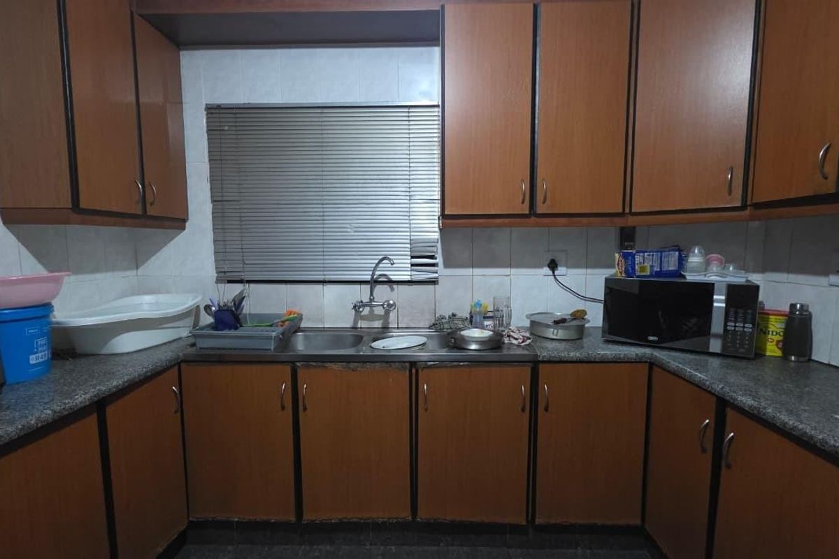 A functional kitchen featuring wood-look laminate cabinetry, granite countertops, and a double basin sink with tiled backsplash.