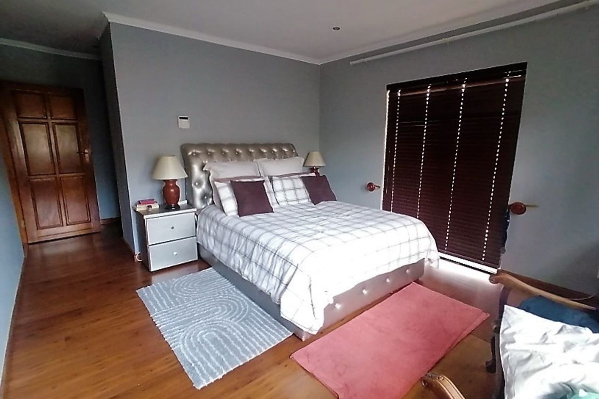 A well-maintained bedroom featuring warm hardwood flooring, recessed lighting, and dark wooden blinds, providing a comfortable and private living space.