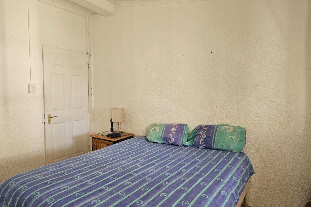 A bedroom featuring textured walls, coving, and tiled flooring, currently requiring cosmetic updates to improve the overall aesthetic and condition.