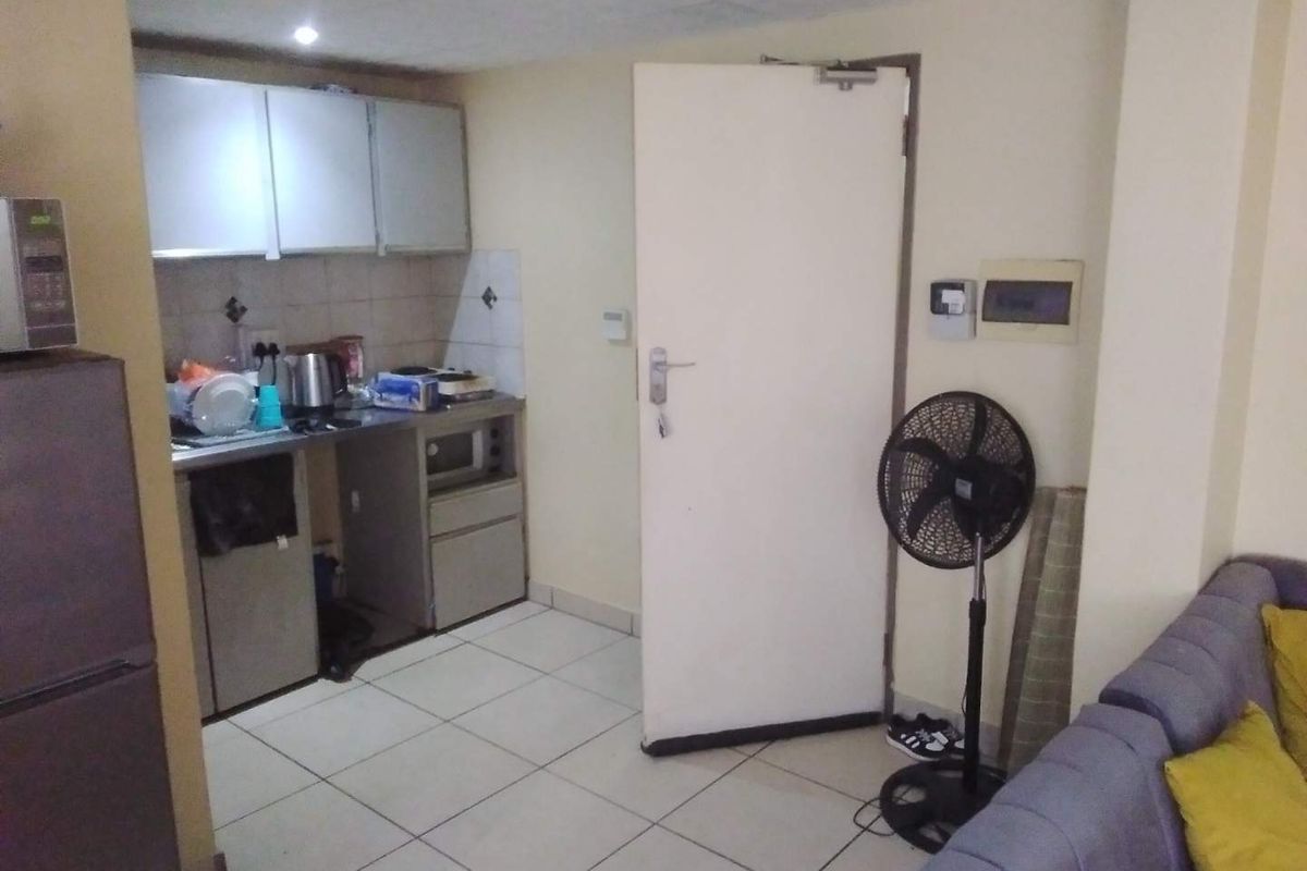 Open plan living area featuring a compact kitchenette with built-in cabinetry and tiled flooring throughout.