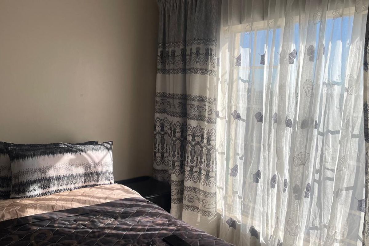 A bedroom featuring natural light through a window with patterned curtains.