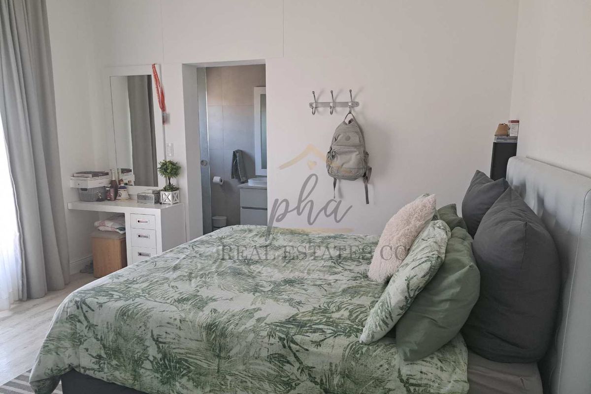 A well-maintained bedroom featuring a built-in vanity area and direct access to an en-suite bathroom.