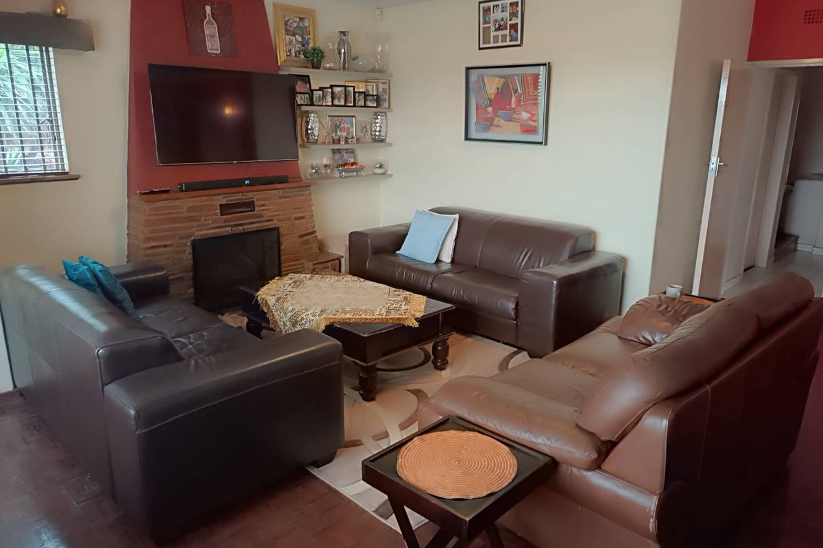 A cozy living room featuring a brick-faced fireplace, parquet flooring, and a neutral wall palette, providing a comfortable and functional family space.