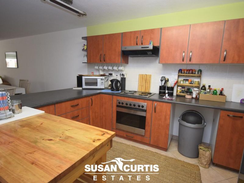 A functional kitchen featuring wood-look laminate cabinetry, dark countertops, a built-in oven with hob, and a central kitchen island for additional workspace.