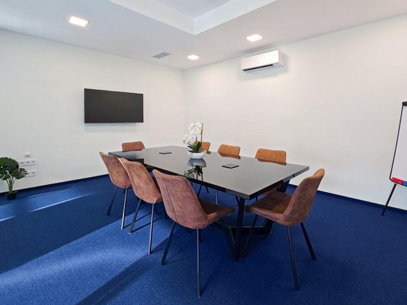 A professional office meeting room featuring a central conference table, wall-mounted television, and integrated air conditioning system.