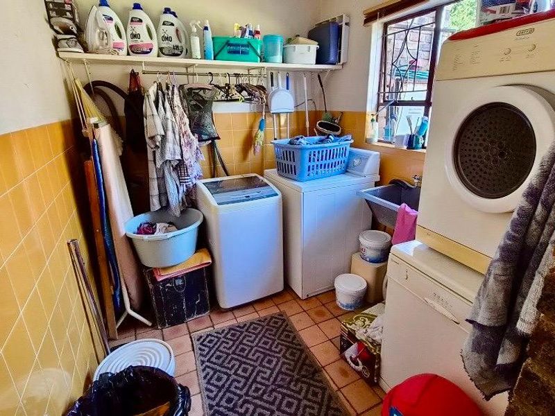 A functional laundry room featuring tiled walls, a utility sink, and built-in shelving, providing a practical space for washing and storage needs.