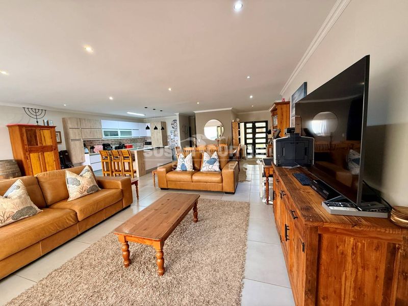 Spacious open-plan living area featuring tiled floors, recessed lighting, and a modern kitchen with a central island and ample built-in cabinetry.