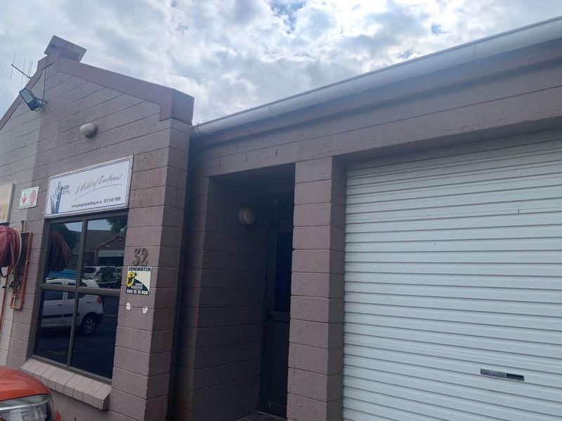 Front elevation of the office building featuring a roller shutter door, large display windows, and exterior signage.