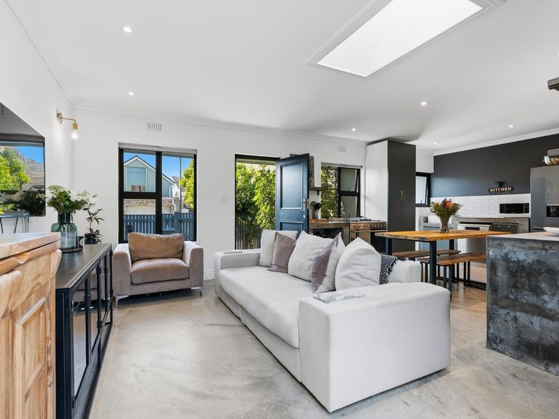 Modern open-plan living and kitchen area featuring polished concrete floors, a large skylight, and contemporary kitchen finishes with integrated appliances.