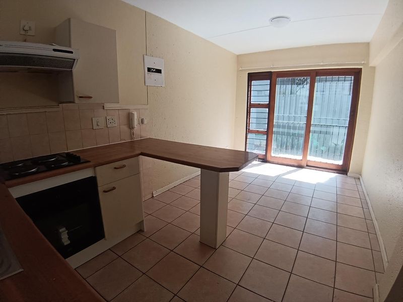 Open-plan kitchen and living area featuring tiled floors, built-in oven and hob, and sliding door access to a balcony.