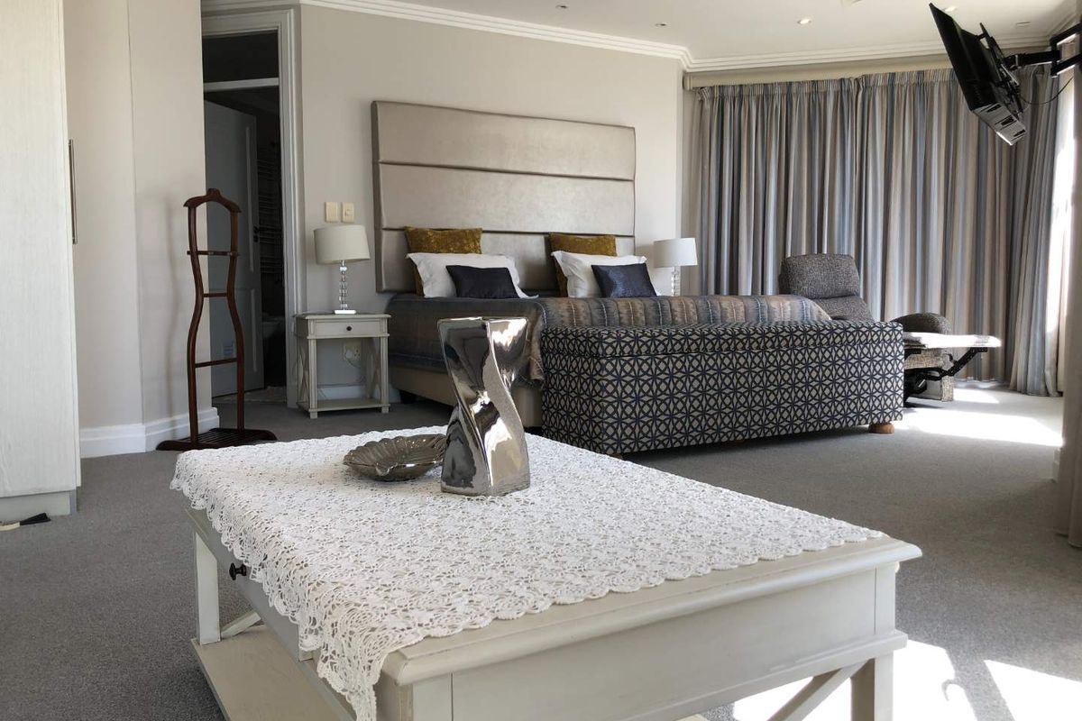 Spacious master bedroom featuring neutral carpeting, recessed ceiling lighting, a ceiling fan, and an integrated wall-mounted television.